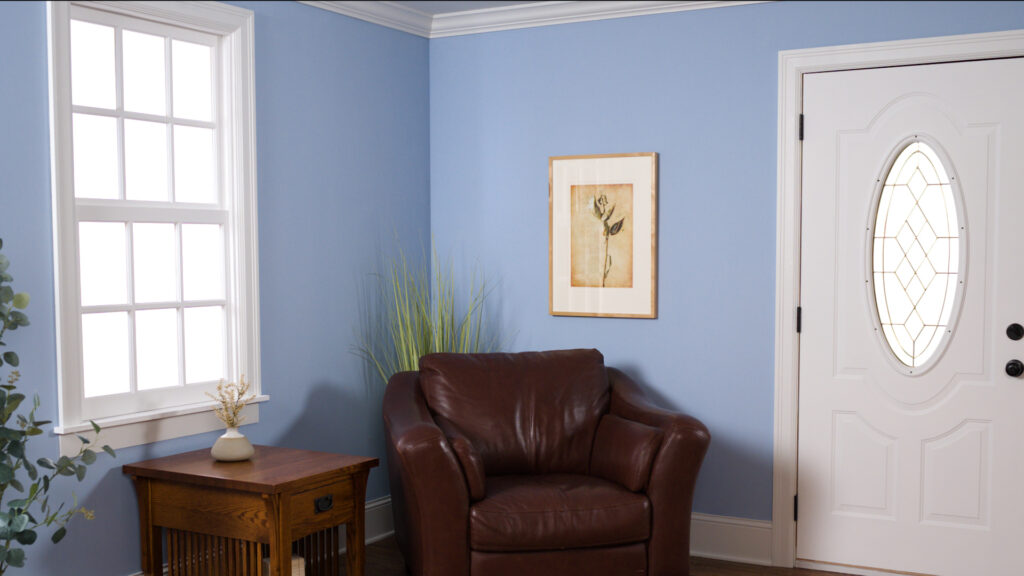 freshly painted room in the color blue, clean room with a chair and side table on the wall with the front door to the house showing