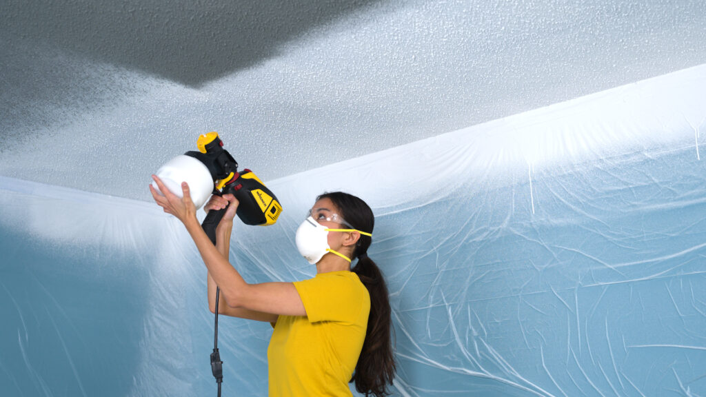 painter spraying the ceiling with the flexio 3500 paint and stain sprayer with glasses and a mask on