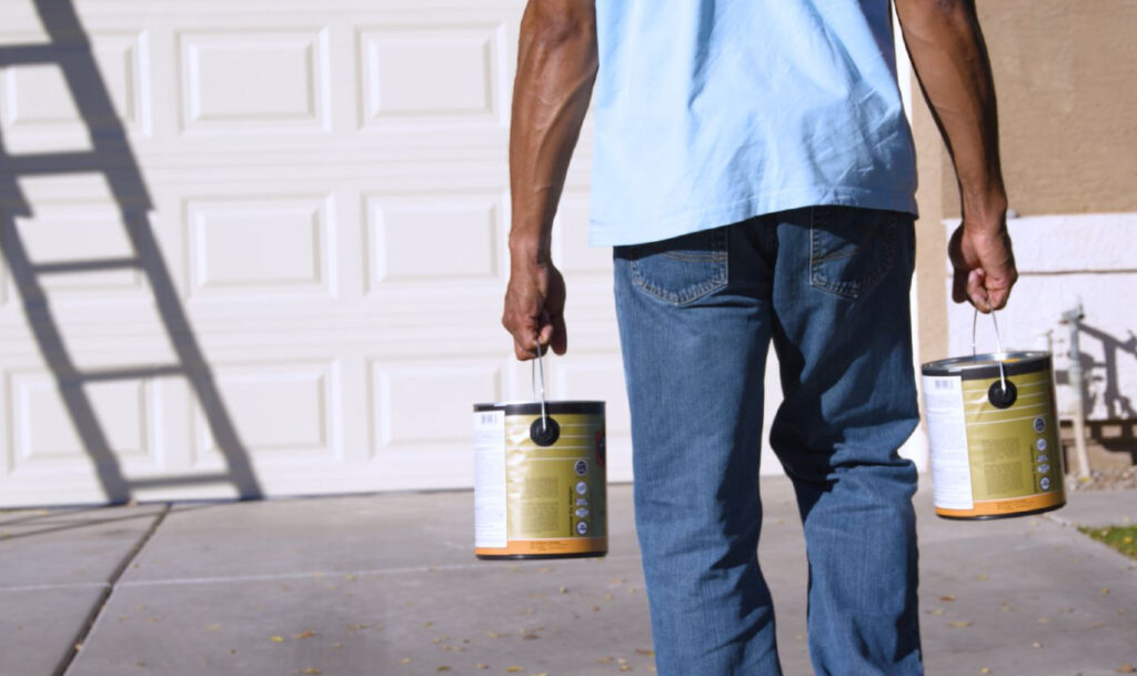 man walking and holding paint cans