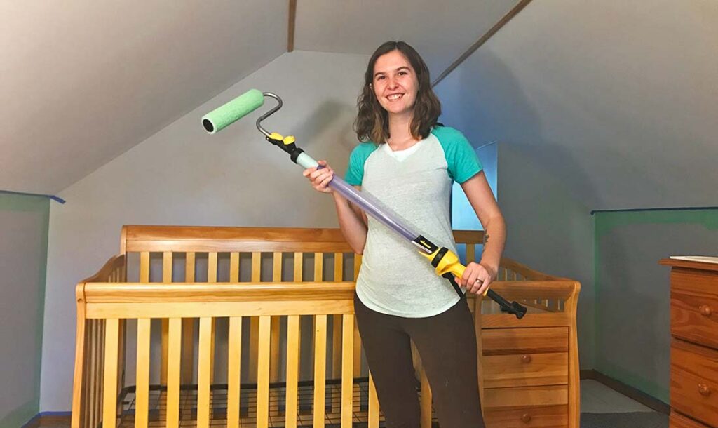 person holding roller in the nursery, getting ready to paint the walls