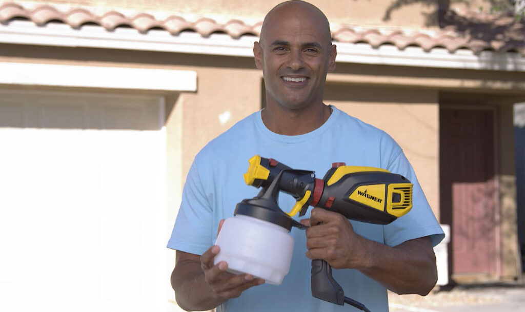 man smiling and holding wagner flexio paint sprayer