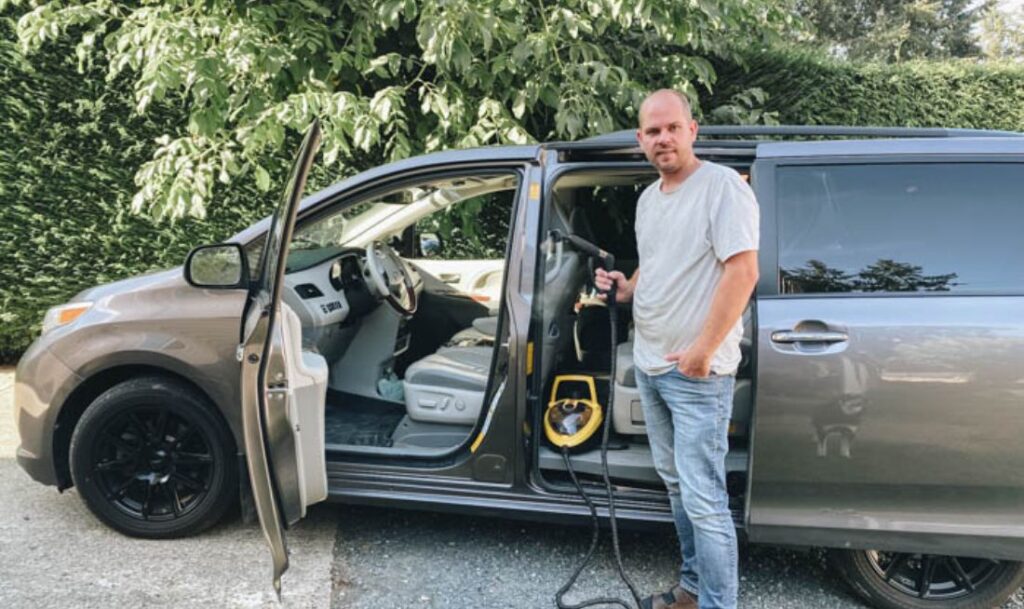 man smiling in front of his car with the 915e Steamer, about to clean his car