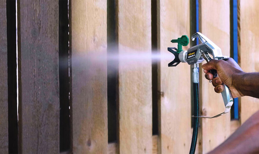 close up of wagner sprayer gun applying stain to a fence
