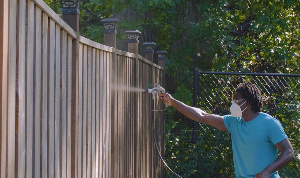 applying stain to a fence